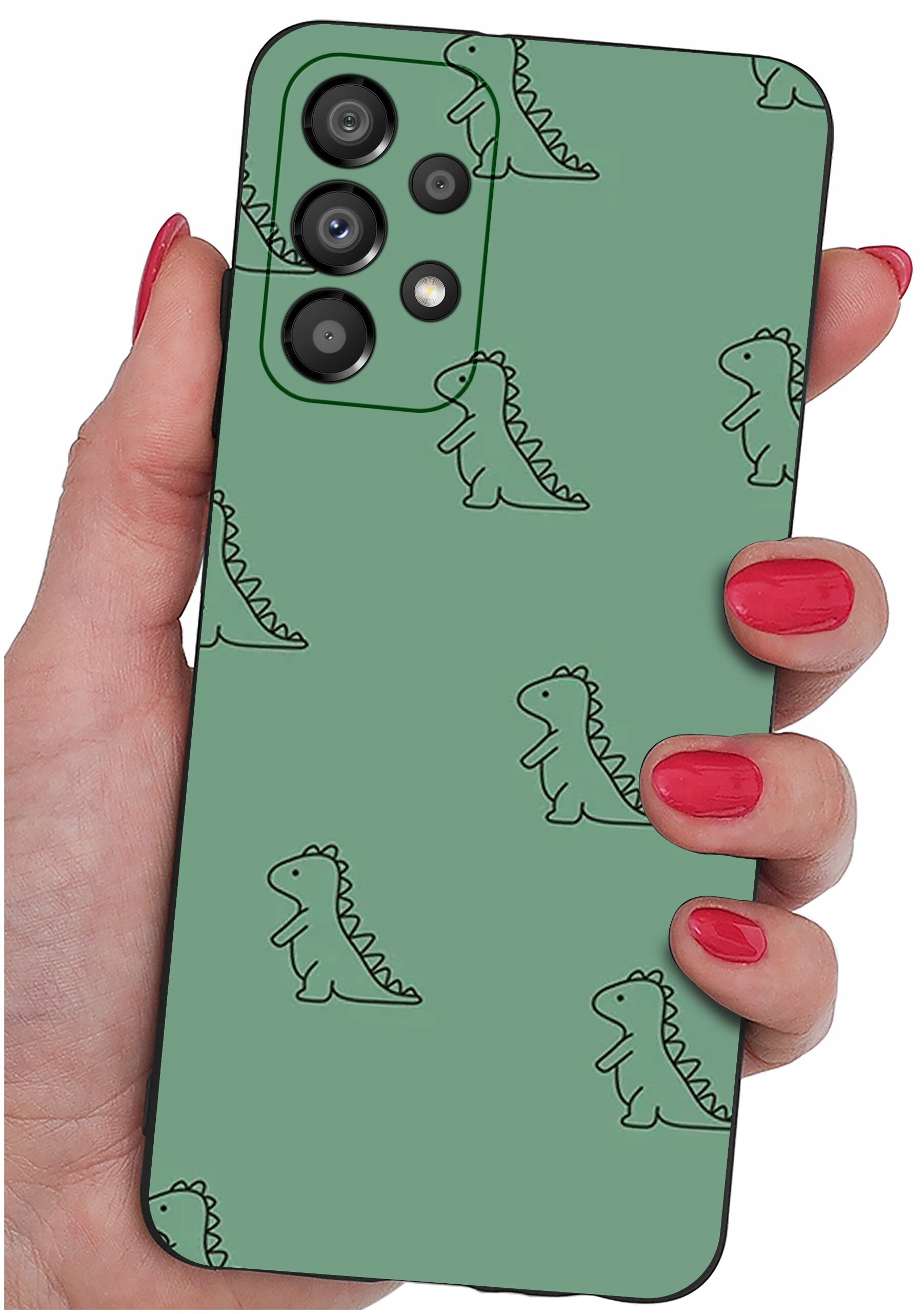 Osoba trzyma telefon w zielonym etui z wzorem małych dinozaurów. Etui ma wycięcia na aparat i przyciski.