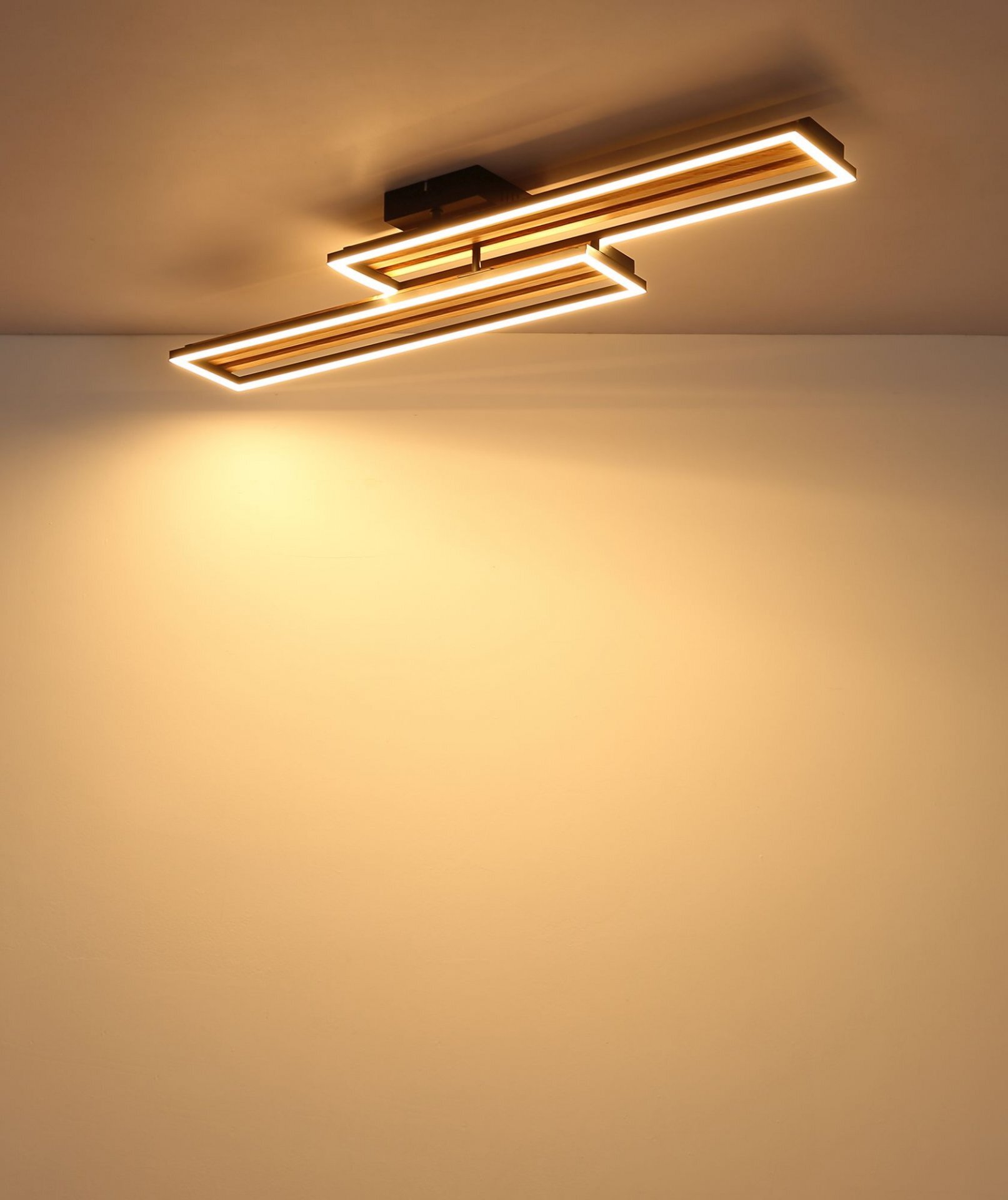 Nowoczesna lampa sufitowa LED o geometrycznym kształcie, emitująca ciepłe światło. Zamontowana jest na suficie, tworząc efektowne oświetlenie pomieszczenia.