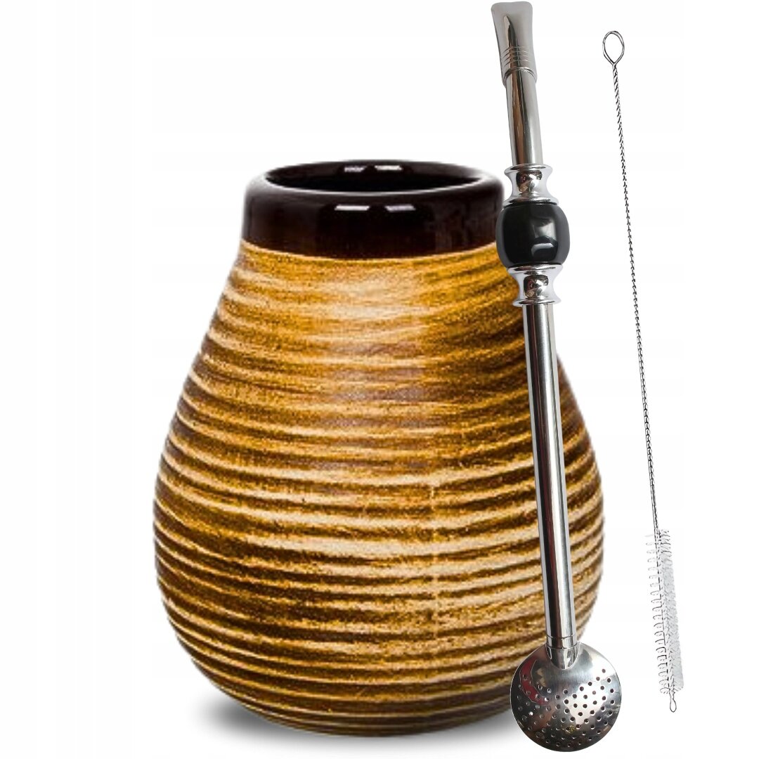 Na obrazie widoczna jest ceramiczna tykwa o miodowym kolorze z ciemnym brzegiem oraz metalowa bombilla z czarnym elementem i sitkiem. Obok znajduje się metalowa szczoteczka do czyszczenia.