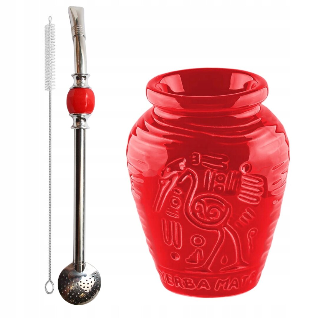 Na obrazie widoczny jest czerwony ceramiczny kubek z azteckimi wzorami oraz metalowa bombilla z czerwonym elementem i czyścikiem. Na kubku znajduje się napis \'YERBA MATE\'.