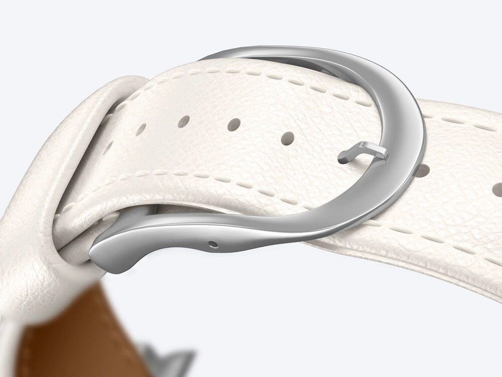 Zbliżenie na srebrne metalowe łączniki jasnobeżowego paska AmazingThing przy złotej kopercie Apple Watch, widok z boku.