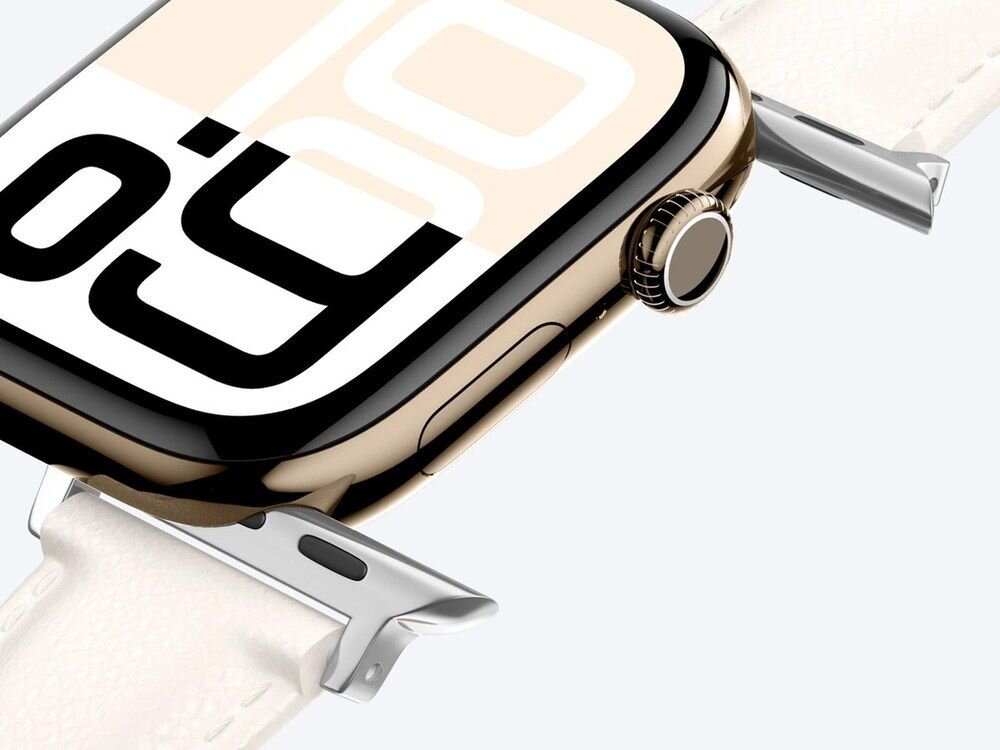 Jasnobeżowy pasek AmazingThing Class Band przy złotej kopercie Apple Watch 46 mm, widok z przodu pod skosem.