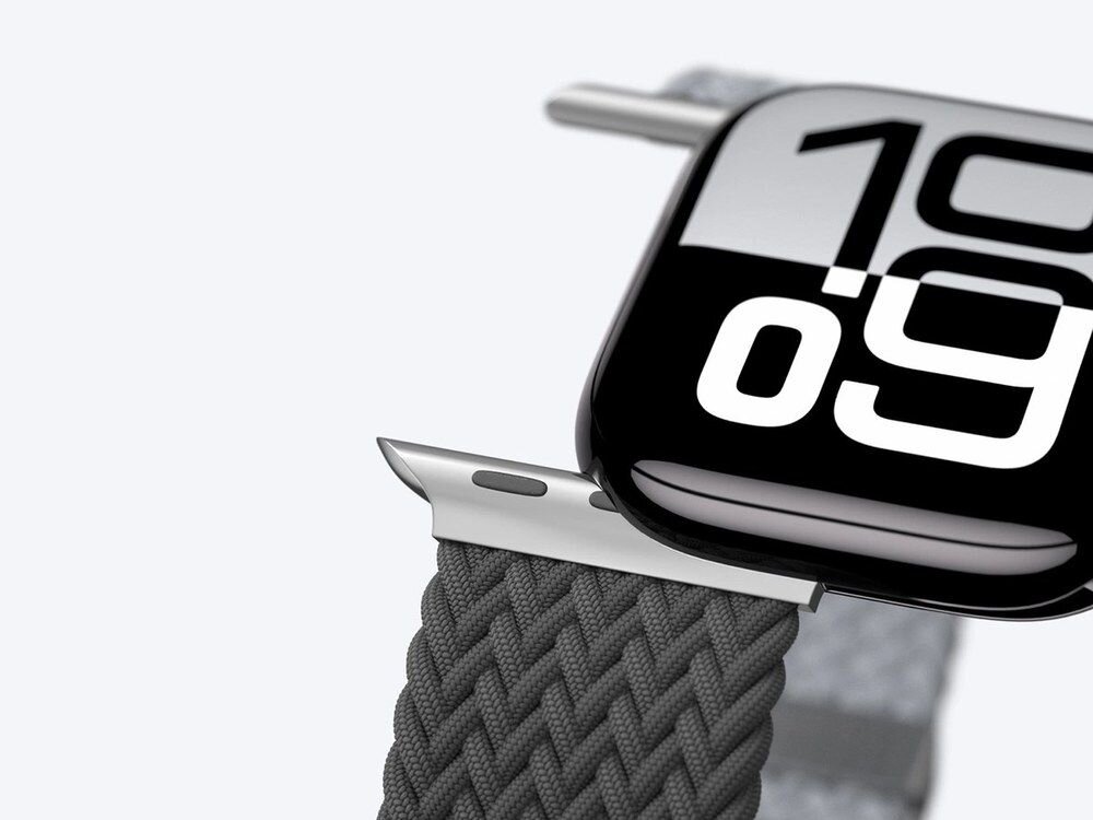 Zbliżenie na srebrzyste ogniwo łączące ciemnoszary pleciony pasek AmazingThing z obudową Apple Watch, ujęcie z boku na białym tle.
