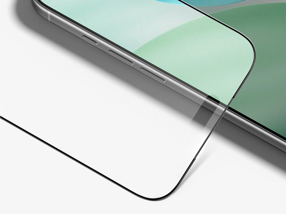 Zbliżenie na narożnik iPhone'a z założonym szkłem ochronnym z czarną ramką, widoczna szczelina między szkłem a smartfonem na jasnym tle.