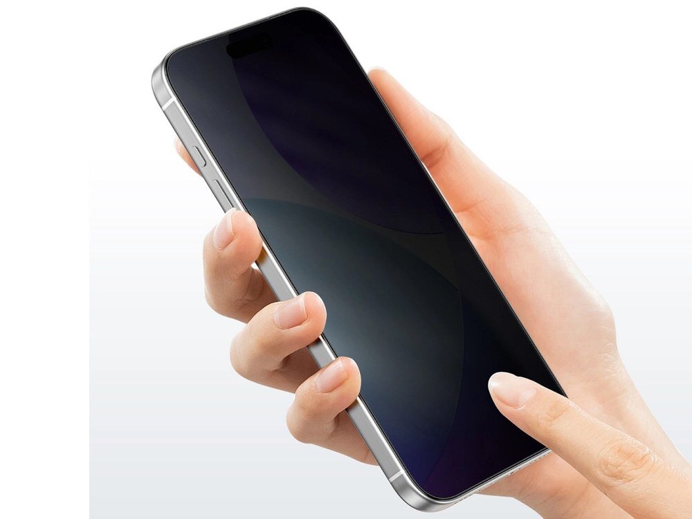 Dłoń trzymająca smartfon z założonym szkłem prywatyzującym, ekran przyciemniony od boku, srebrna ramka telefonu widoczna na białym tle.