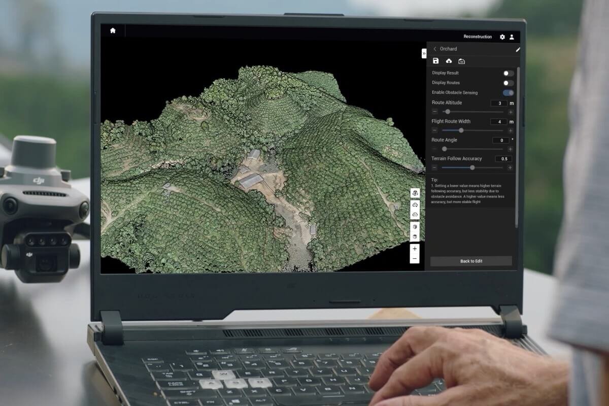 Na ekranie laptopa wyświetlany jest trójwymiarowy model terenu z gęstą roślinnością. Obok laptopa znajduje się urządzenie z logo \'DJI\'.