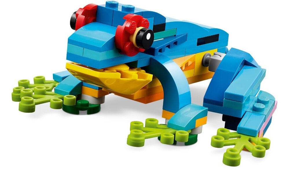Model z klocków LEGO przedstawiający kolorową żabę z czerwonymi oczami i zielonymi łapkami. Żaba zbudowana jest z niebieskich, żółtych i zielonych elementów.