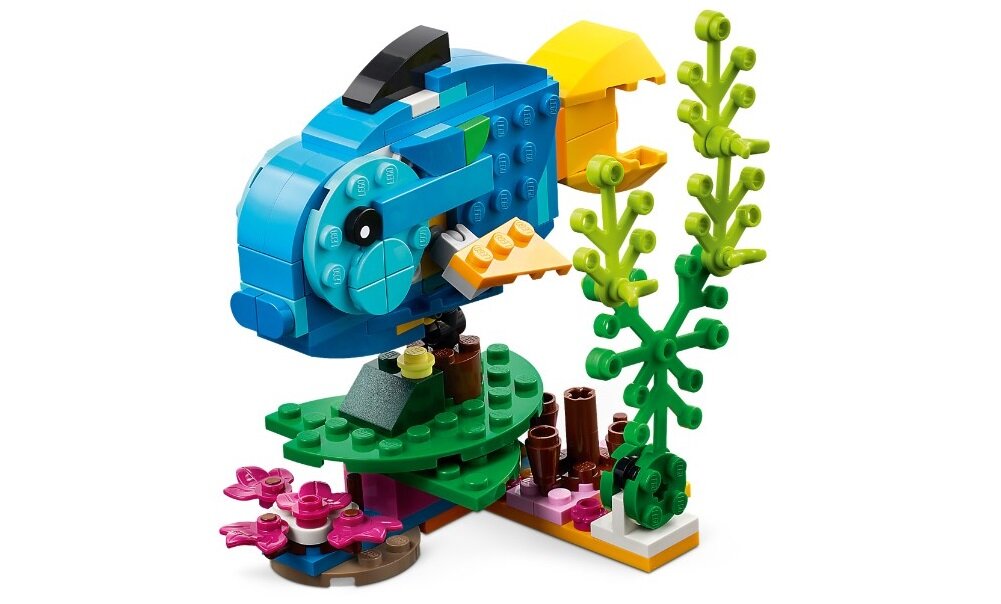 Zestaw LEGO przedstawiający kolorową rybę zbudowaną z klocków, otoczoną elementami przypominającymi rośliny wodne. Rybka ma niebieskie, żółte i pomarańczowe elementy oraz czarne oko.