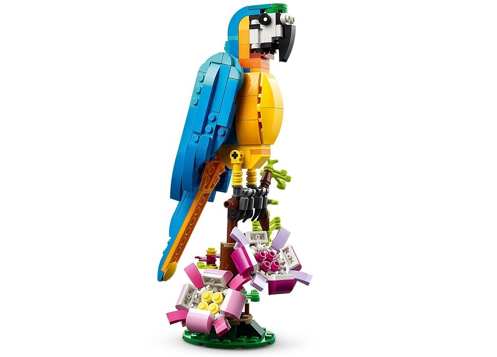 Model papugi z klocków LEGO w kolorach niebieskim, żółtym i zielonym, stojący na gałęzi z różowymi kwiatami.