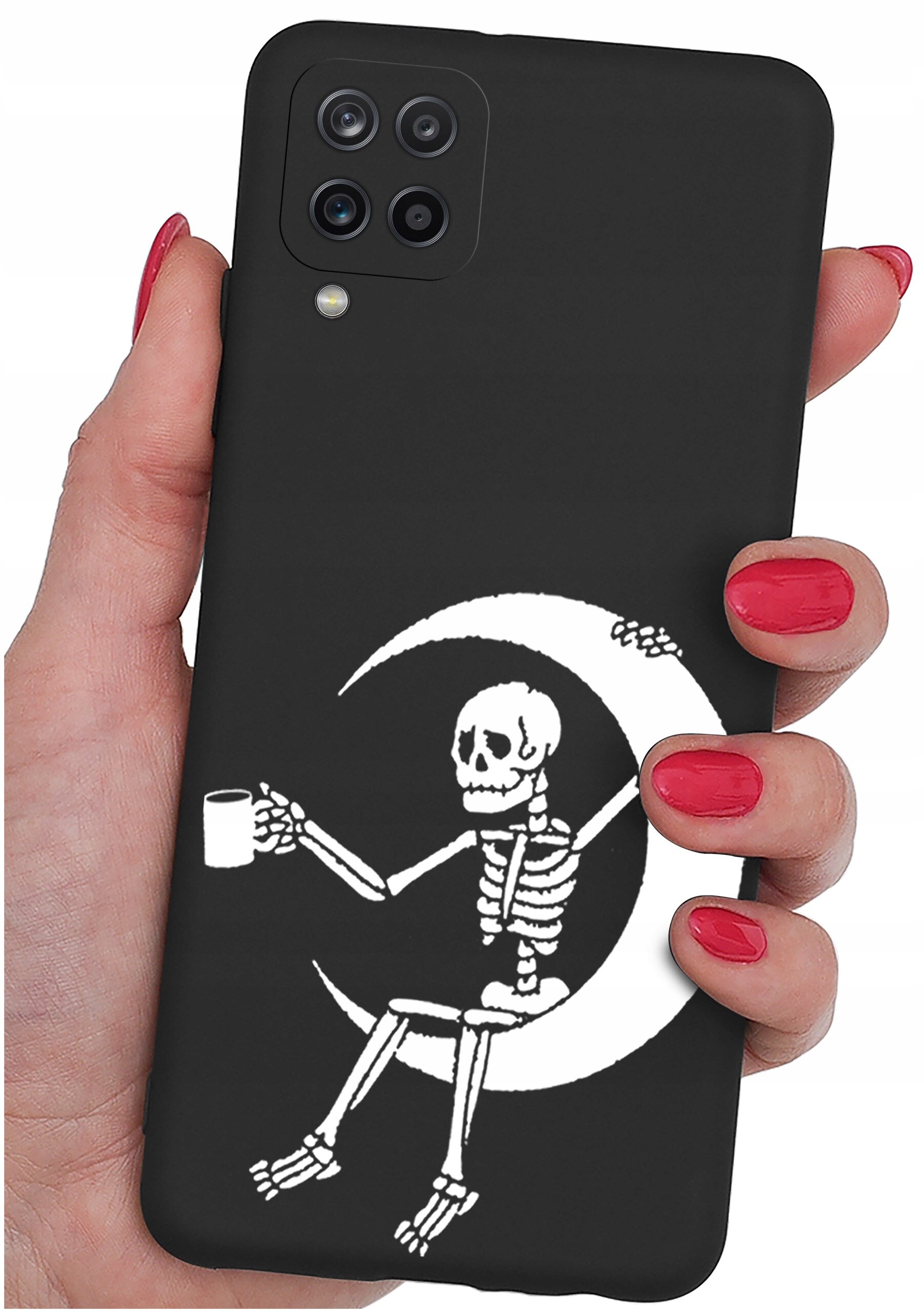 Czarne etui na telefon z nadrukiem białego szkieletu siedzącego na księżycu, trzymającego kubek. Etui jest trzymane w dłoni z pomalowanymi na czerwono paznokciami.