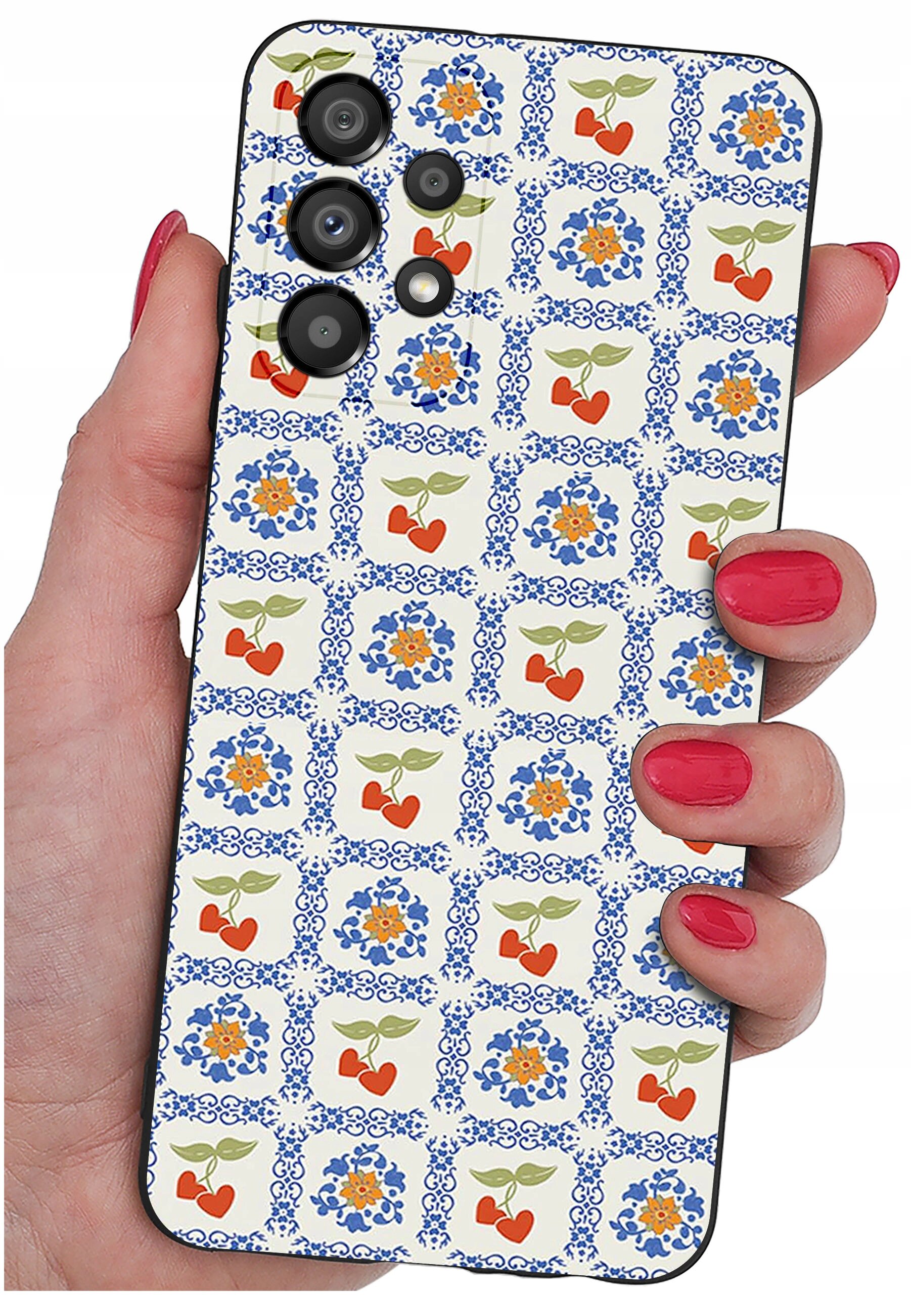 Osoba trzyma telefon z etui ozdobionym wzorem w niebieskie ornamenty i czerwone serca z zielonymi liśćmi. Etui ma wycięcia na cztery obiektywy aparatu.