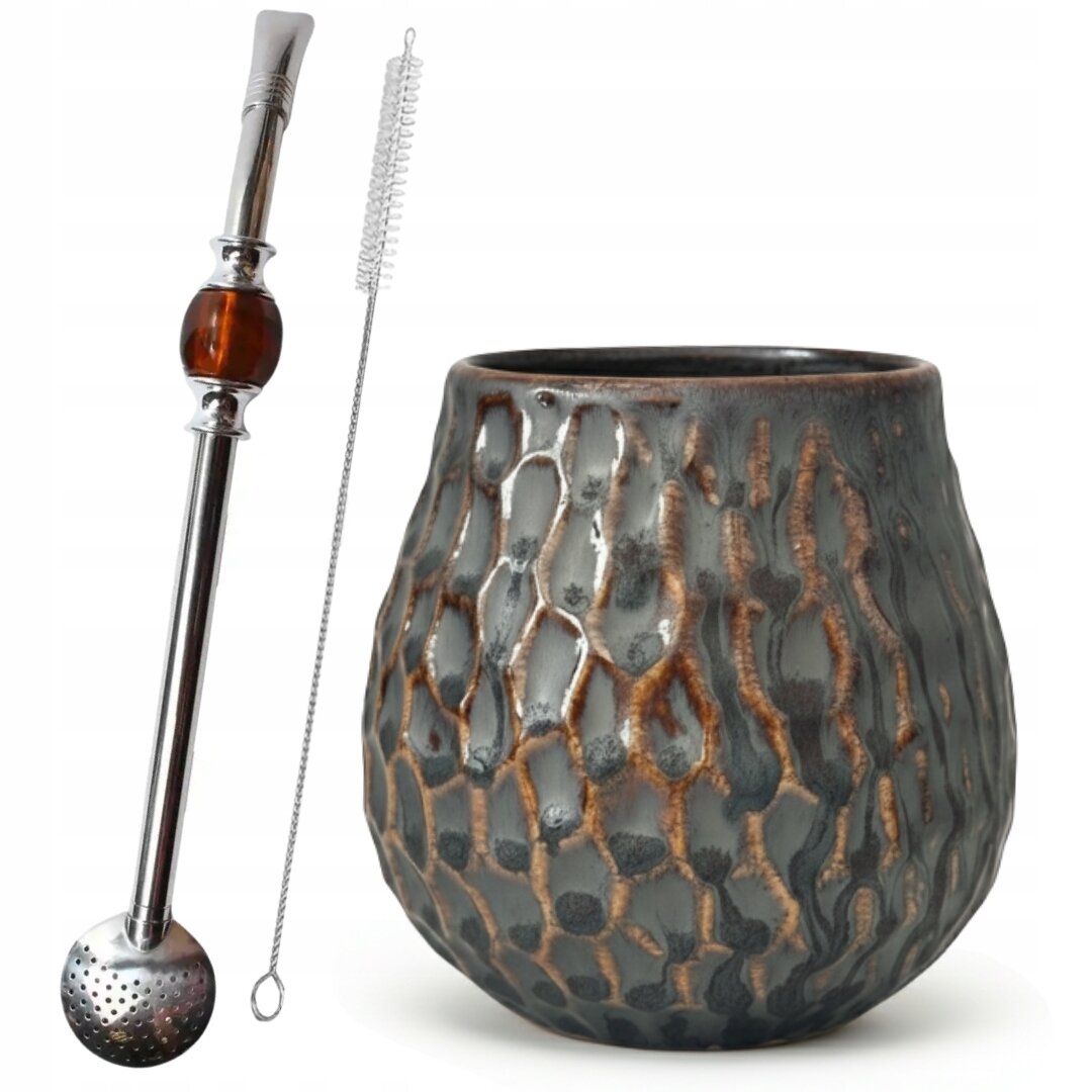 Na obrazie widoczny jest zestaw do yerba mate składający się z ceramicznego naczynia o fakturze przypominającej plaster miodu, metalowej bombilli z ozdobnym elementem oraz szczoteczki do czyszczenia. Naczynie ma ciemny kolor z brązowymi akcentami.