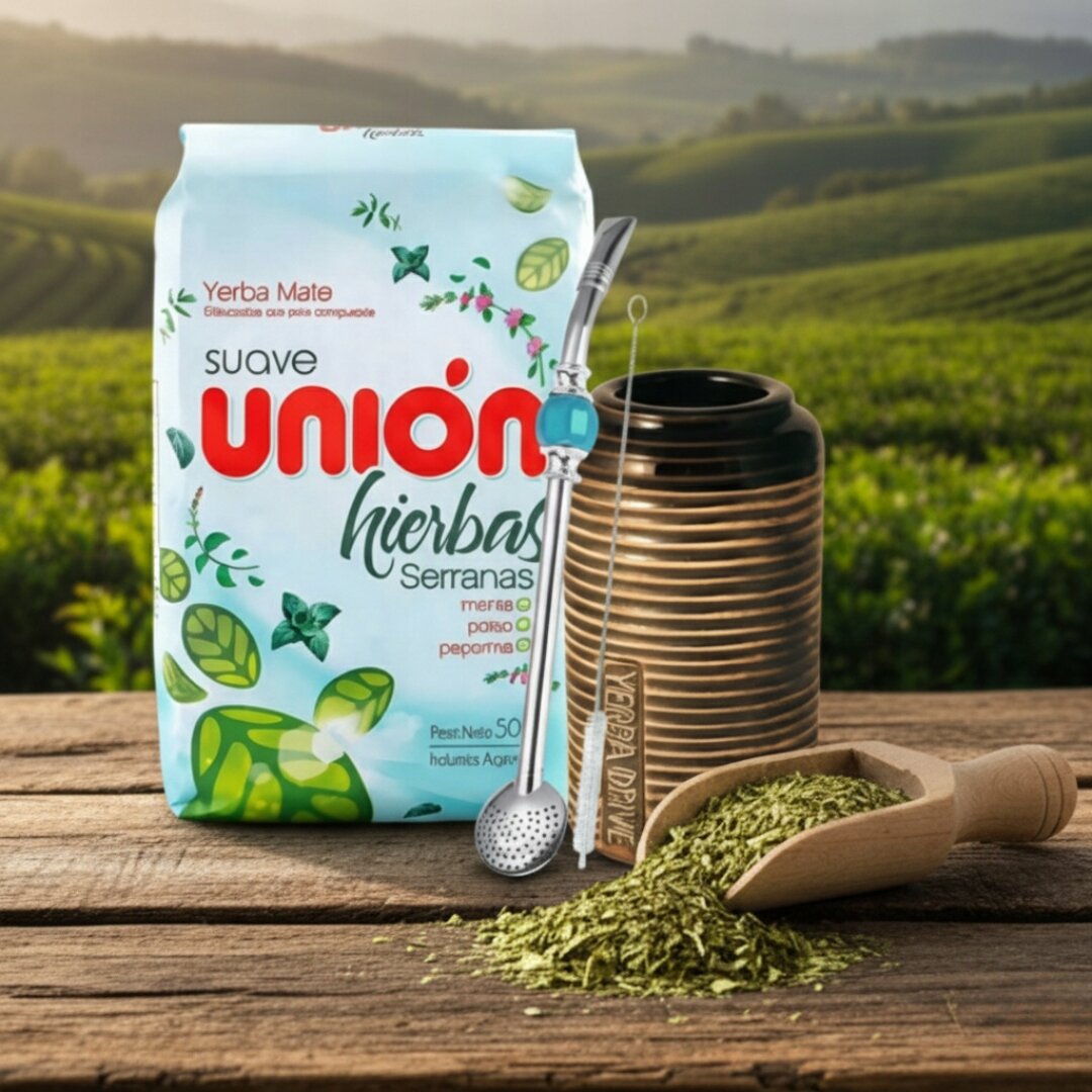 Na drewnianym stole znajduje się opakowanie Yerba Mate Union Hierbas Serranas, metalowa bombilla, ceramiczne matero oraz drewniana łyżka z suszem yerba mate. W tle widoczny jest zielony krajobraz z polami uprawnymi.