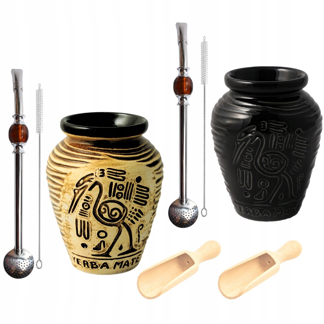 Na obrazie znajdują się dwa ceramiczne naczynia do yerba mate z azteckimi wzorami, jedno w kolorze beżowym z napisem \'Yerba Mate\', drugie czarne. Obok nich widoczne są dwie metalowe bombille z czyszczakami oraz dwie drewniane łyżeczki.
