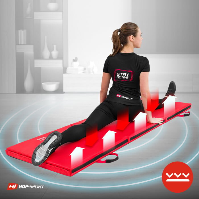 Osoba siedzi na czerwonym, składanym materacu gimnastycznym z rzepami marki HOP-SPORT. Na koszulce widoczny jest napis \'STAY ACTIVE\', a w tle znajduje się wnętrze pokoju.