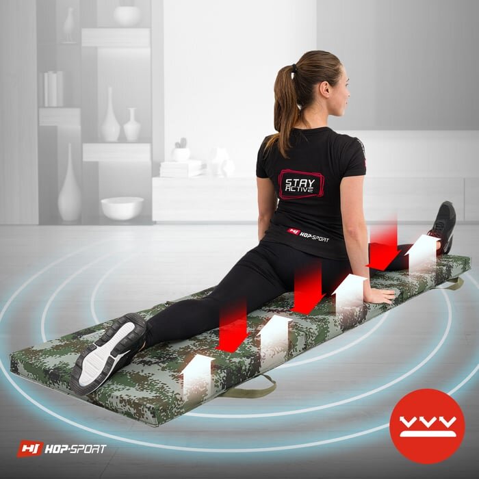 Osoba siedzi na składanym materacu gimnastycznym w kolorze moro, wykonując ćwiczenie rozciągające. Na koszulce widoczny jest napis \'STAY ACTIVE\', a w rogu znajduje się logo \'HJ HOP-SPORT\'.