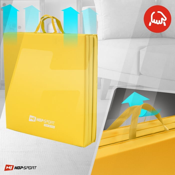 Żółty, składany materac gimnastyczny z uchwytami, oznaczony logo \'HOP-SPORT\'. W tle widoczna jest część wnętrza z sofą oraz niebieskie strzałki wskazujące na funkcję składania.