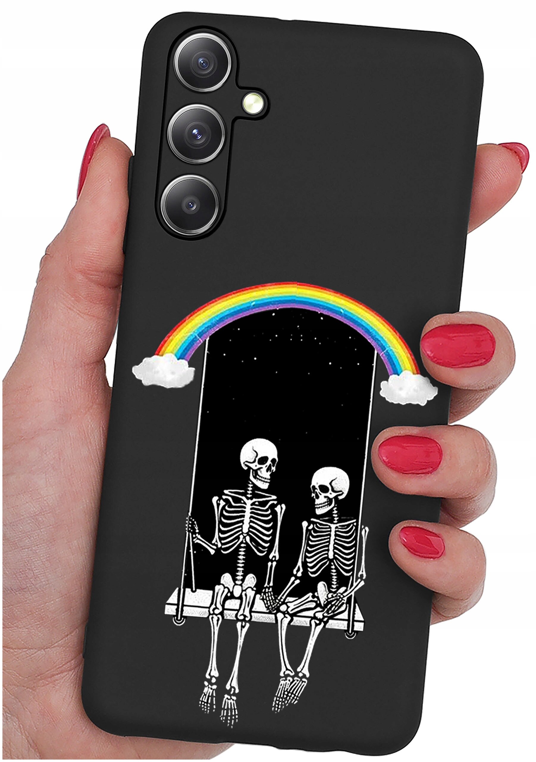 Czarne etui na telefon z grafiką przedstawiającą dwa szkielety siedzące na huśtawce pod tęczą z chmurkami. Etui trzymane jest w dłoni z pomalowanymi na czerwono paznokciami.