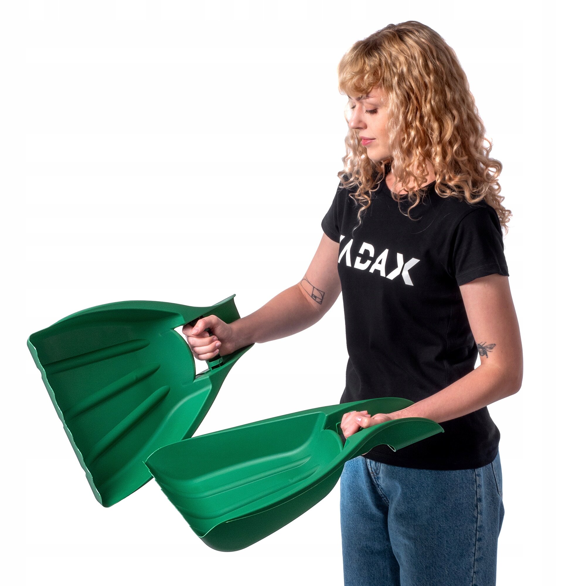 Osoba trzyma dwa zielone plastikowe narzędzia ogrodowe przypominające łapy niedźwiedzia. Na koszulce widoczny jest napis \'ACAX\'.