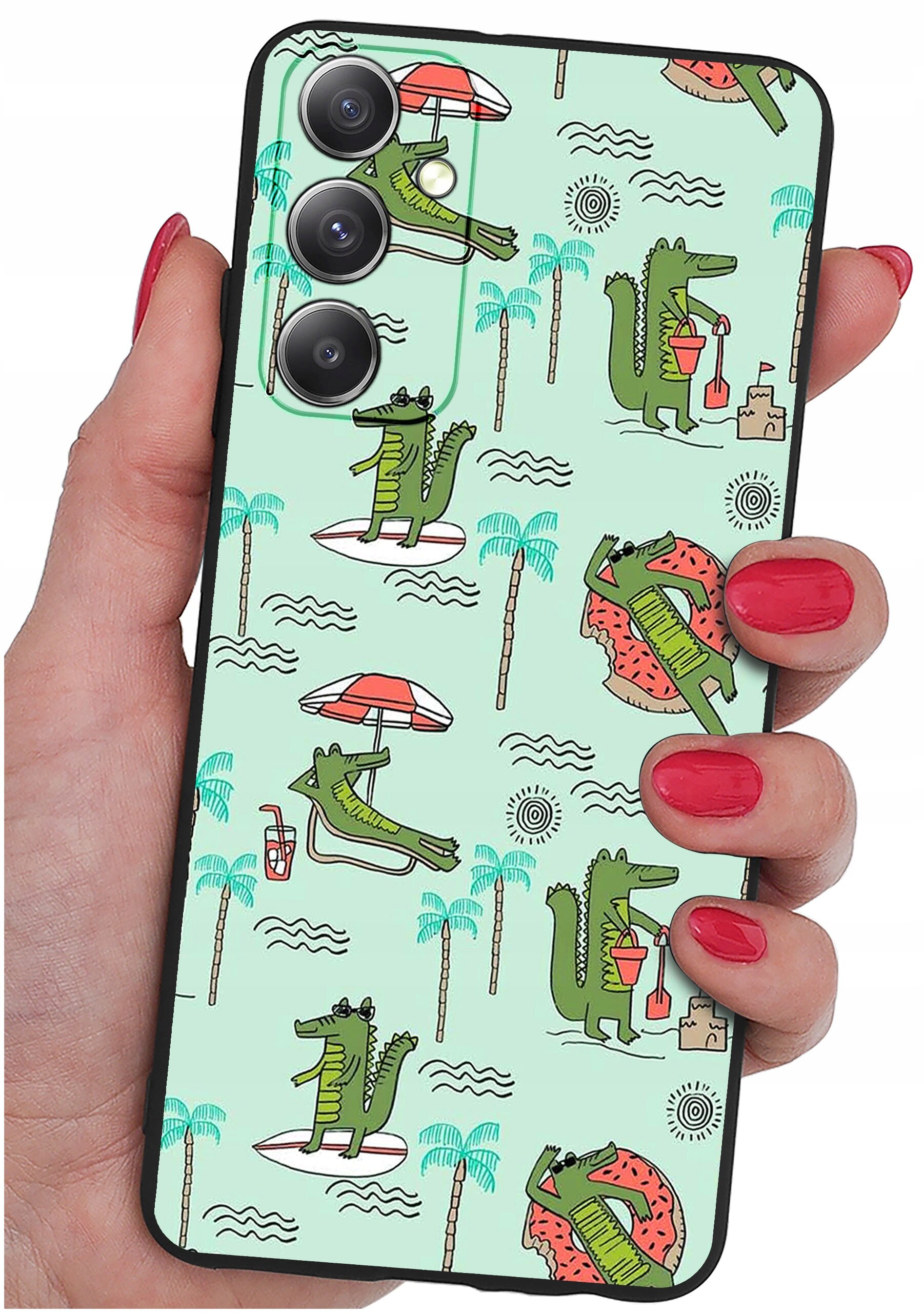 Etui na telefon z wzorem przedstawiającym zielone krokodyle w różnych pozach, otoczone palmami, parasolami i falami na jasnym tle. Etui trzymane jest w dłoni z pomalowanymi na czerwono paznokciami.