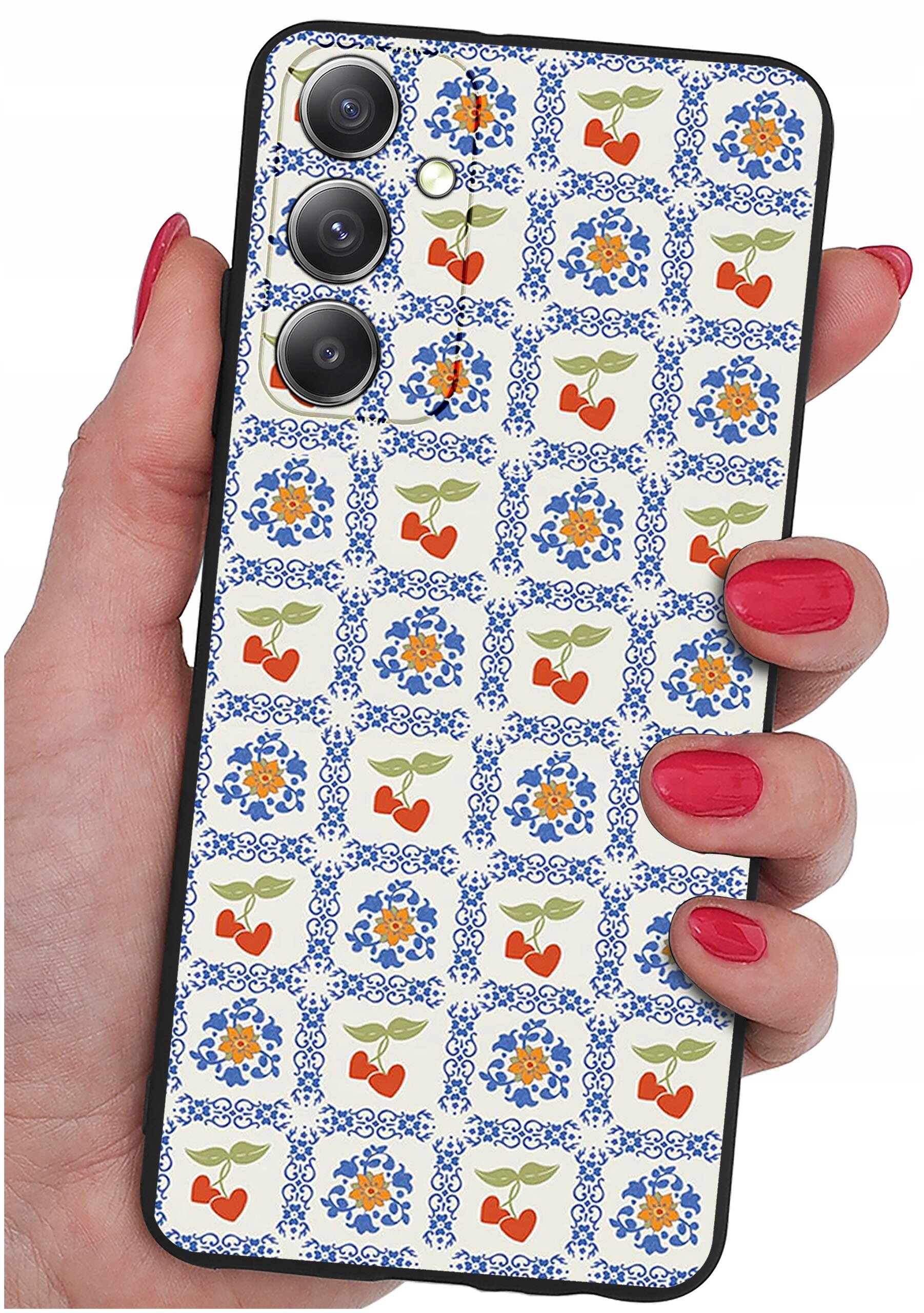 Osoba trzyma telefon z etui ozdobionym wzorem w niebieskie i pomarańczowe kwiaty oraz czerwone serca z zielonymi liśćmi. Etui ma wycięcia na trzy obiektywy aparatu i lampę błyskową.