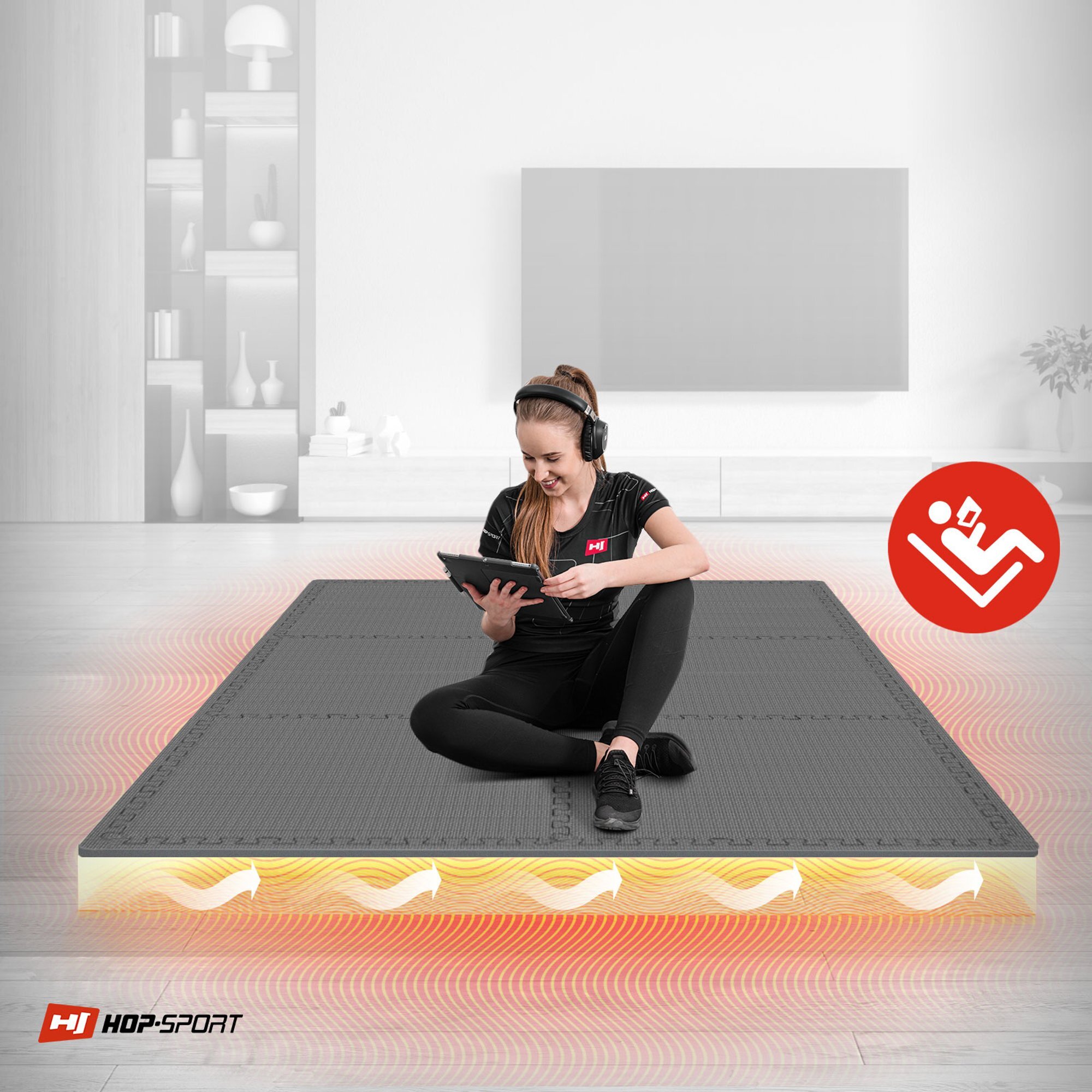 Osoba siedzi na szarej macie puzzle EVA, trzymając tablet. W rogu widoczne jest logo HOP-SPORT oraz czerwony symbol osoby ćwiczącej.