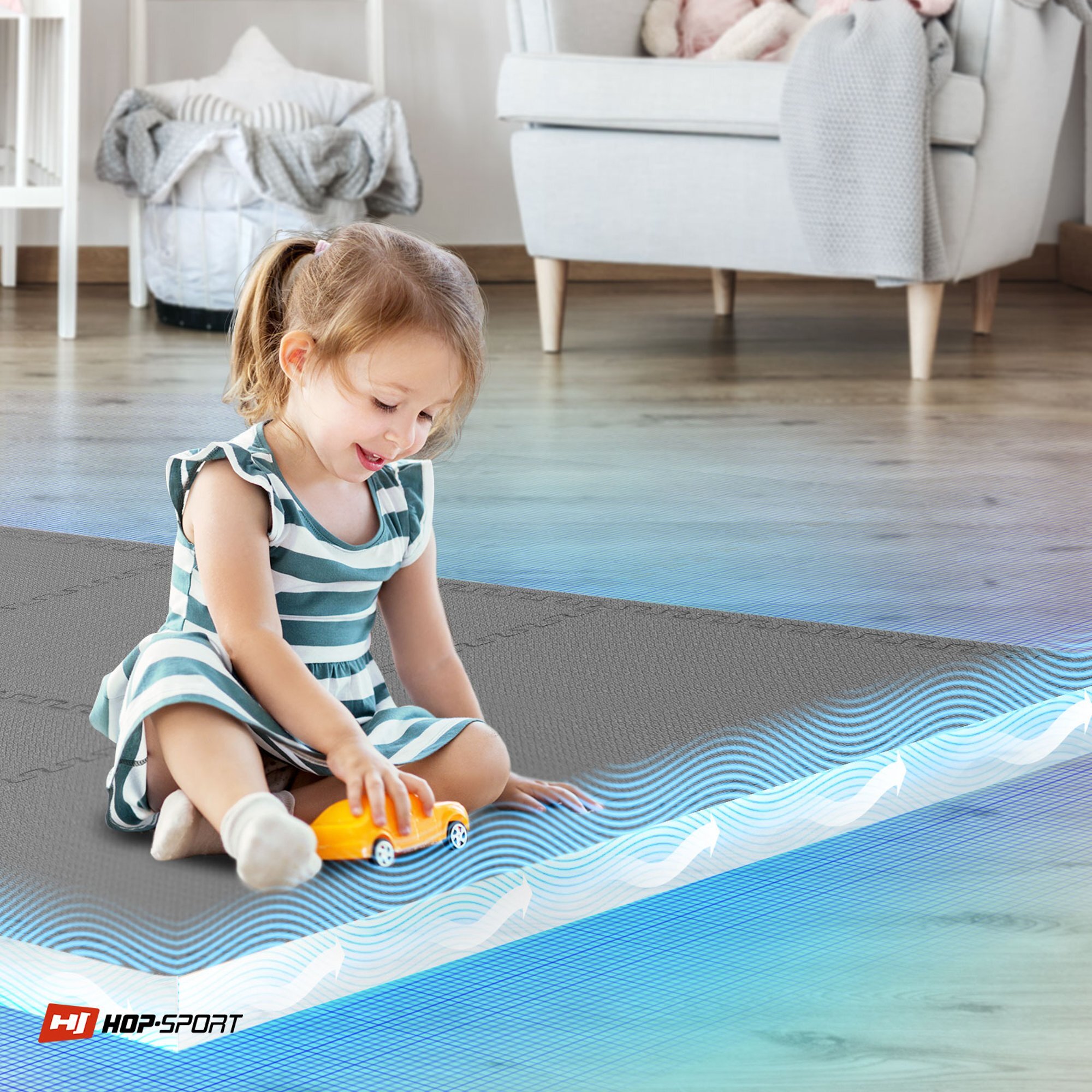 Dziewczynka w sukience w paski bawi się żółtym samochodzikiem na szarej macie puzzle. W rogu widoczne jest logo \'HOP-SPORT\'.