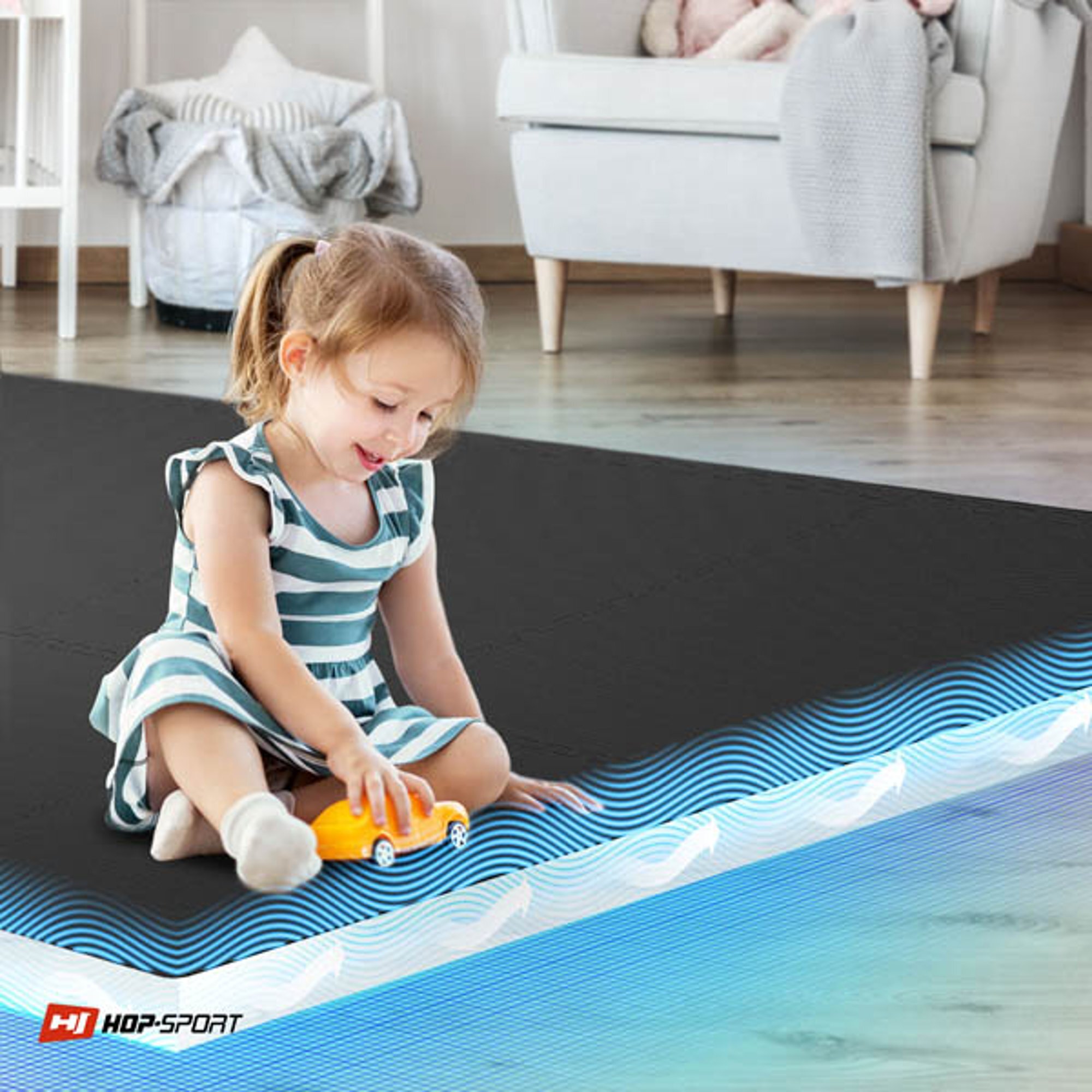 Dziewczynka bawi się żółtym samochodzikiem na czarnej macie puzzle EVA. W rogu widoczne jest logo \'HOP-SPORT\'.
