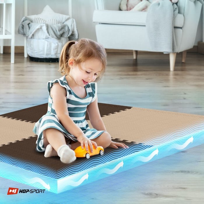 Dziecko siedzi na brązowo-beżowej macie puzzle EVA, bawiąc się żółtym samochodzikiem. W rogu widoczne jest logo \'HOP-SPORT\'.