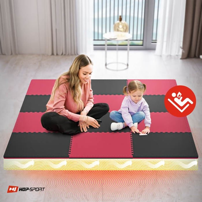 Na obrazie widać dwie osoby siedzące na macie puzzle w kolorach czarnym i czerwonym. W lewym dolnym rogu znajduje się logo \'HOP-SPORT\'.