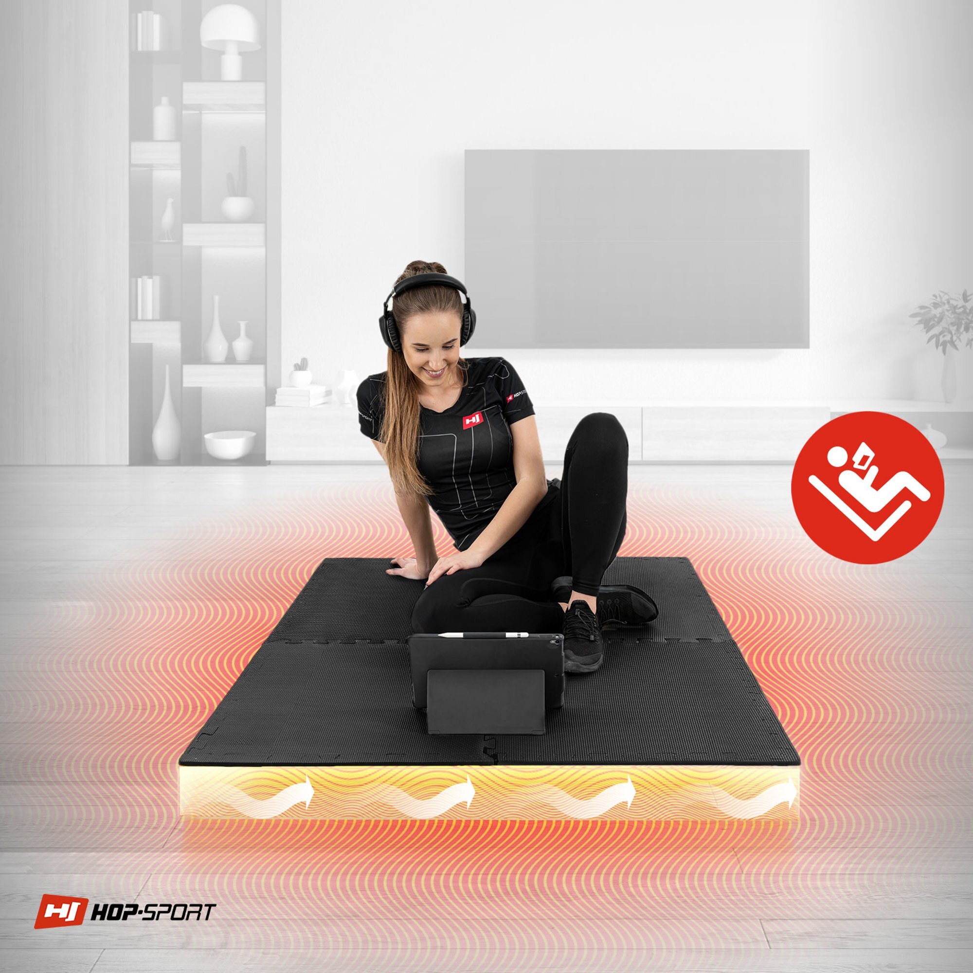 Osoba siedzi na czarnej macie puzzle EVA, ubrana w sportowy strój i słuchawki, przed nią znajduje się tablet. W tle widoczne jest logo HOP-SPORT oraz czerwony symbol z postacią siedzącą z książką.