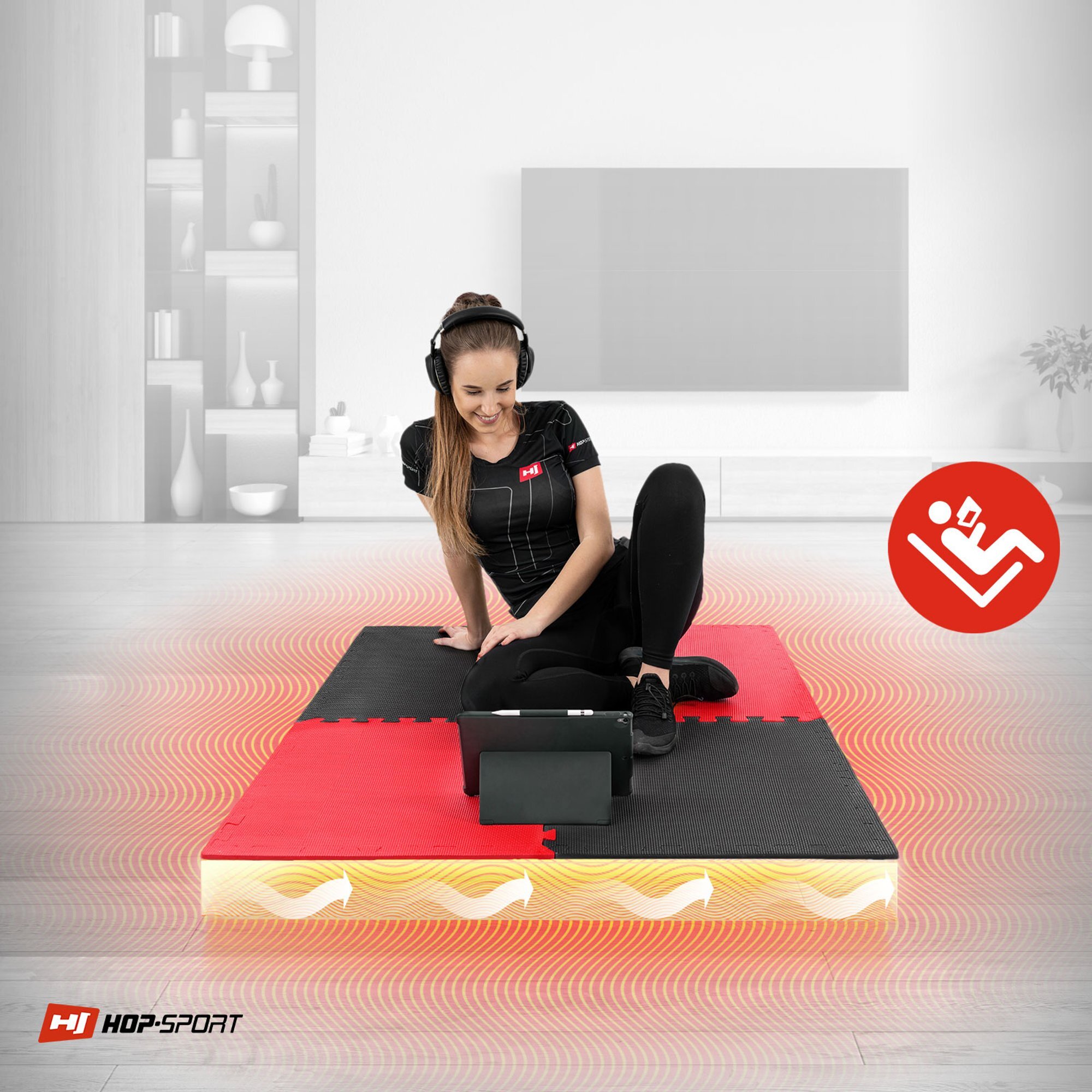 Osoba siedzi na macie puzzle EVA w kolorach czarnym i czerwonym, z tabletem przed sobą. W lewym dolnym rogu widoczne jest logo \'HOP-SPORT\'.