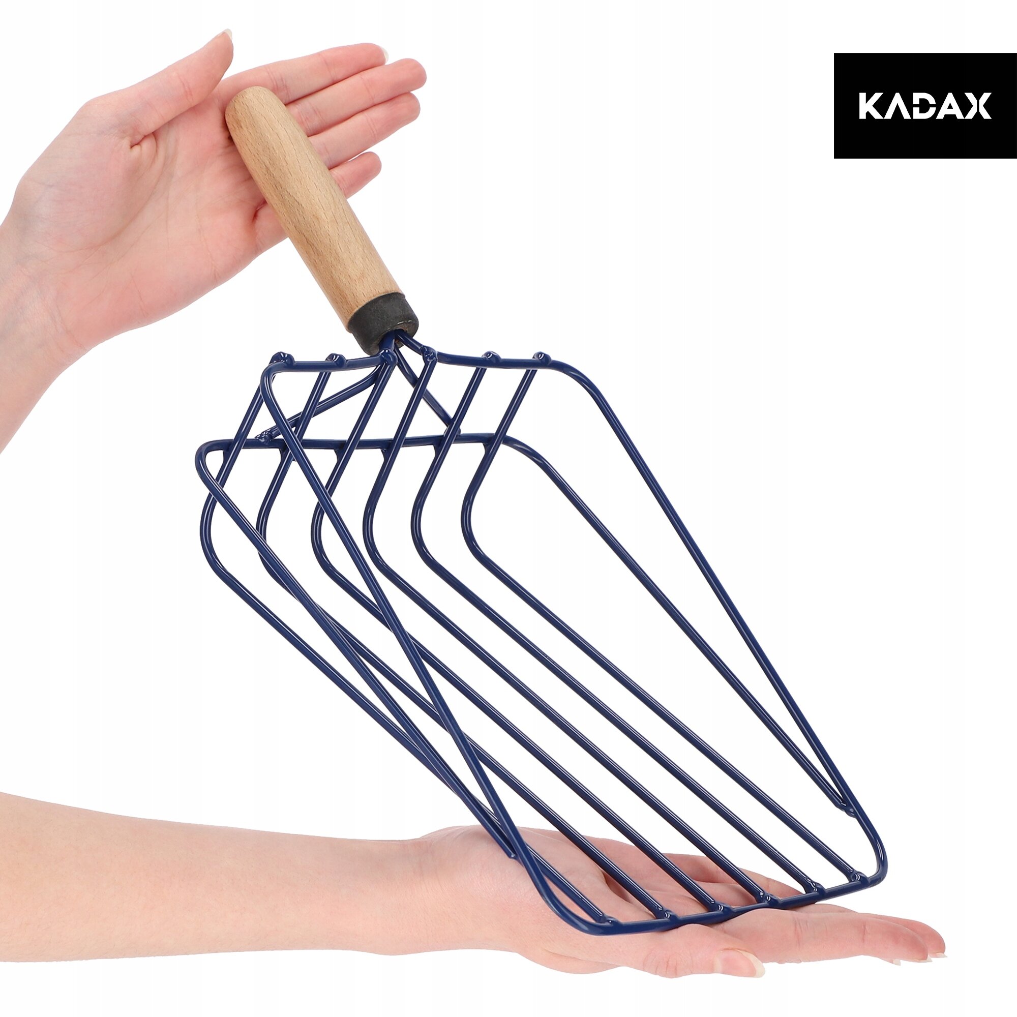 Osoba trzyma metalowy nabierak z drewnianą rączką, składający się z kilku równoległych prętów. W prawym górnym rogu widoczne jest logo \'KADAX\'.