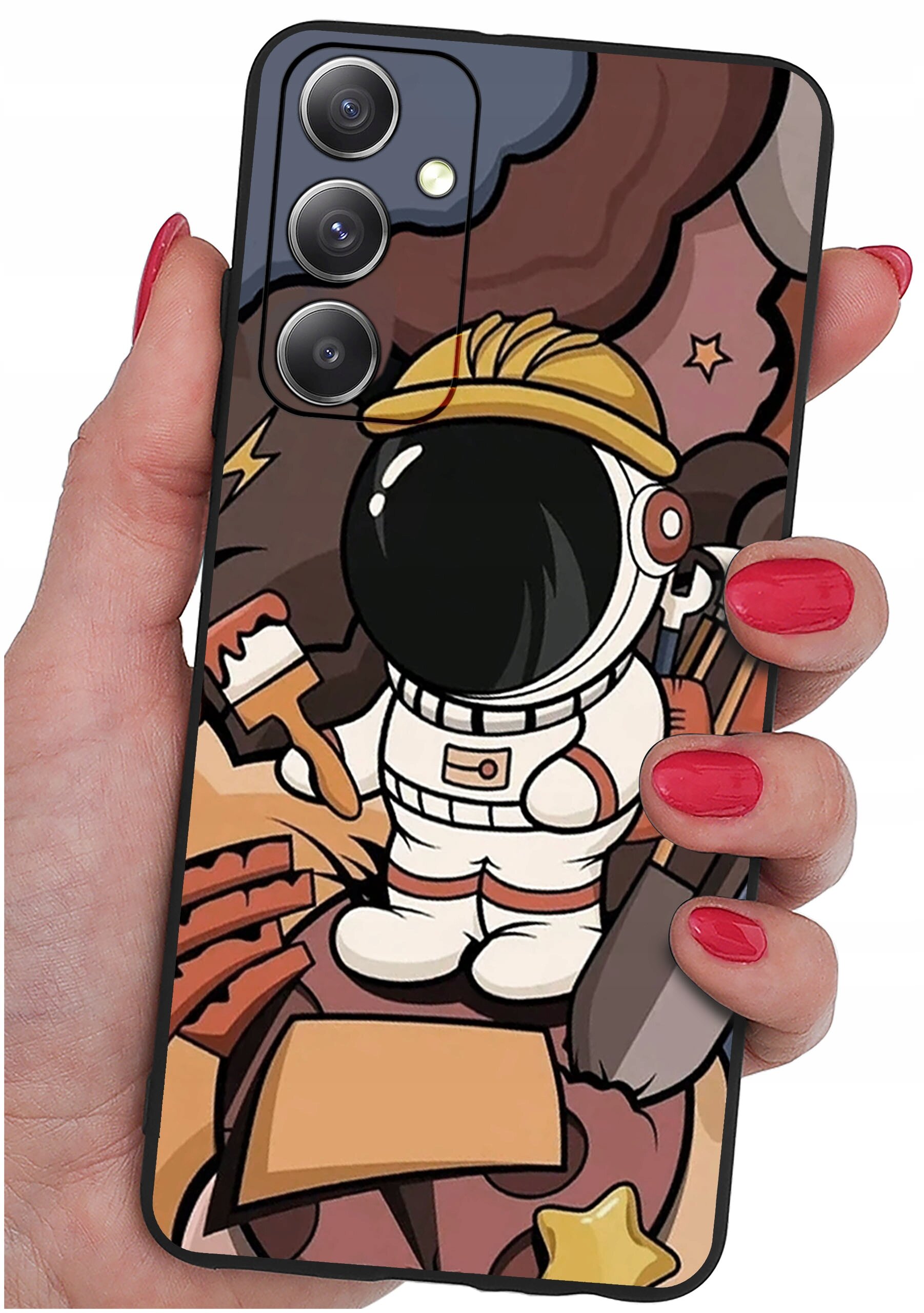 Etui na telefon z kolorowym wzorem przedstawiającym astronautę w kasku, trzymającego pędzel i łopatę. Etui jest trzymane w dłoni z pomalowanymi na czerwono paznokciami.