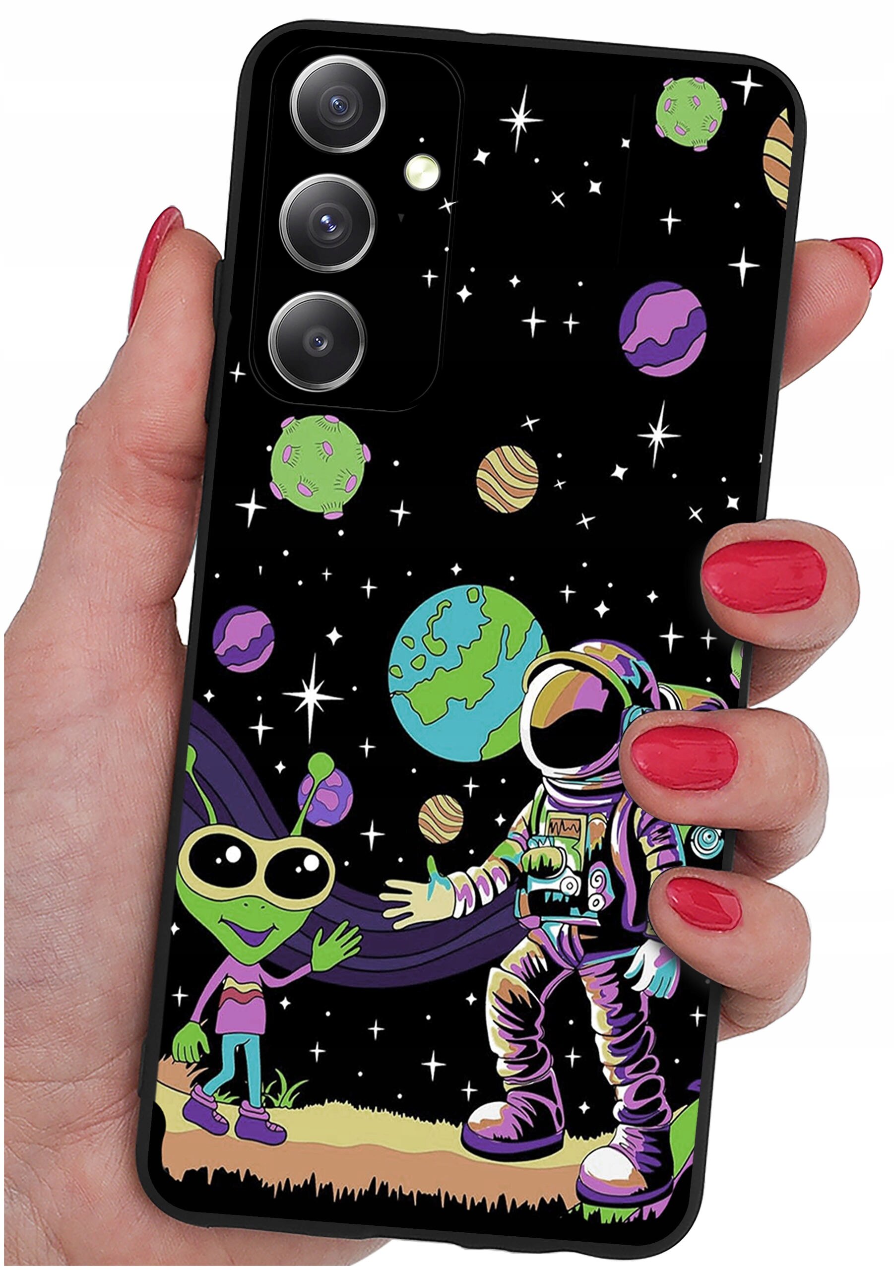 Etui na telefon z kolorowym wzorem przedstawiającym kosmonautę i zielonego kosmitę na tle kosmosu z planetami i gwiazdami. Etui trzymane jest w dłoni z pomalowanymi na czerwono paznokciami.