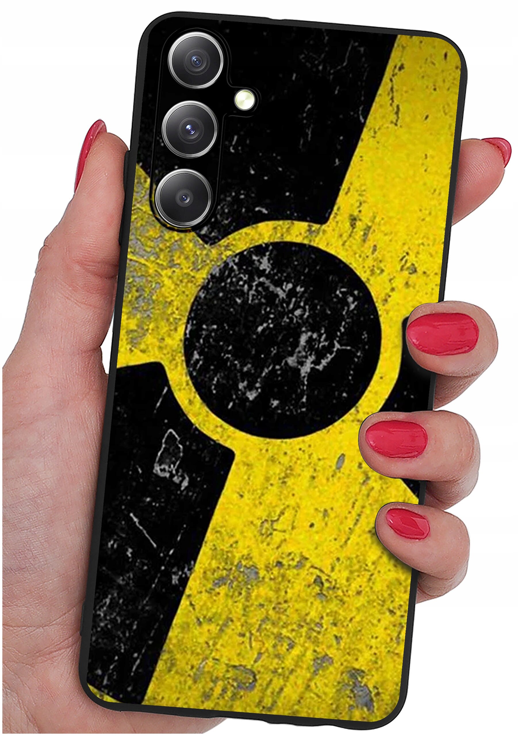 Osoba trzyma telefon z etui o wzorze przypominającym symbol radioaktywności w kolorach żółtym i czarnym. Etui ma matowe wykończenie z widocznymi śladami zużycia.