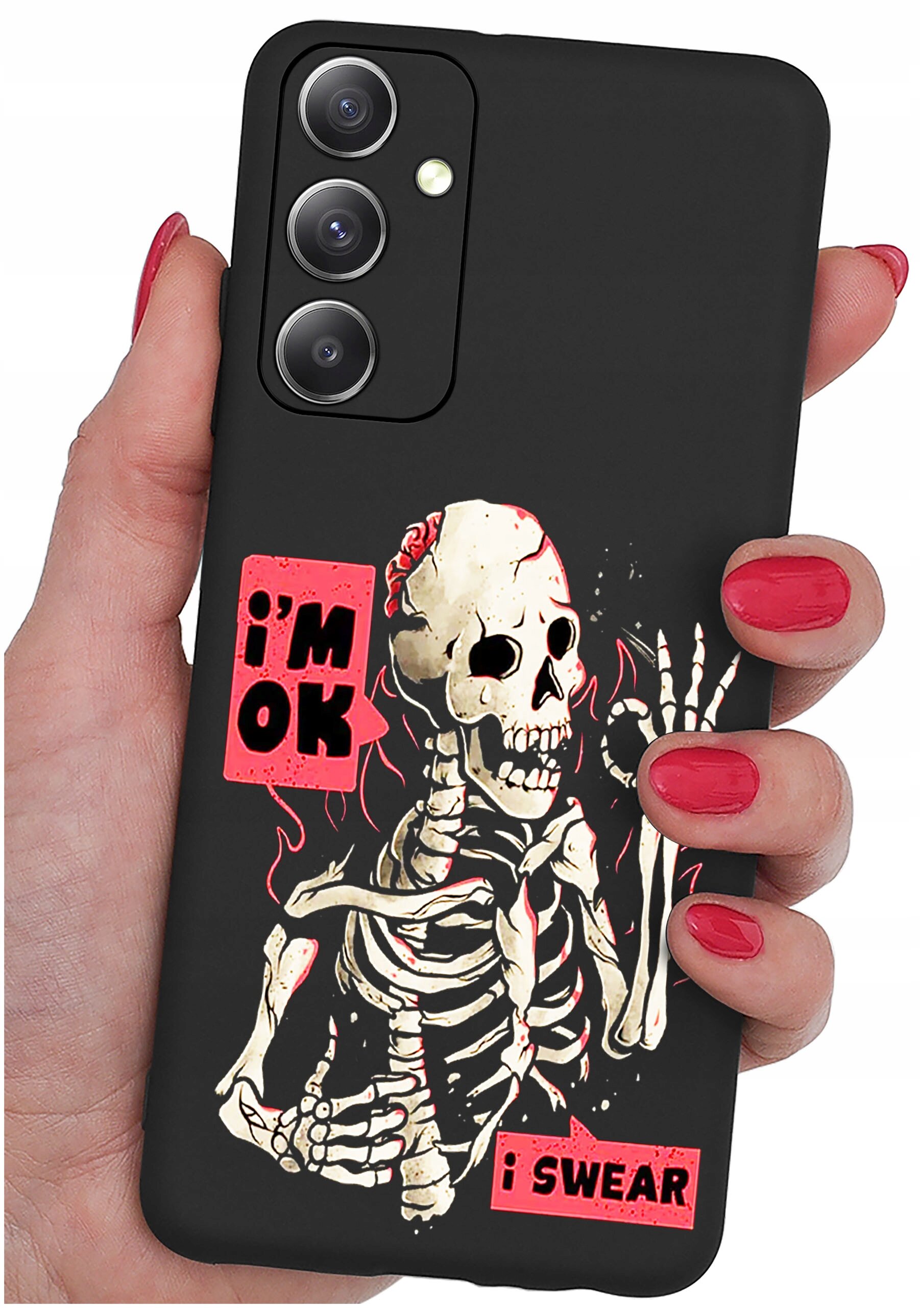 Czarna obudowa telefonu z nadrukiem szkieletu i napisami \'i\'m OK\' oraz \'i SWEAR\'. Obudowa trzymana jest w dłoni z pomalowanymi na czerwono paznokciami.