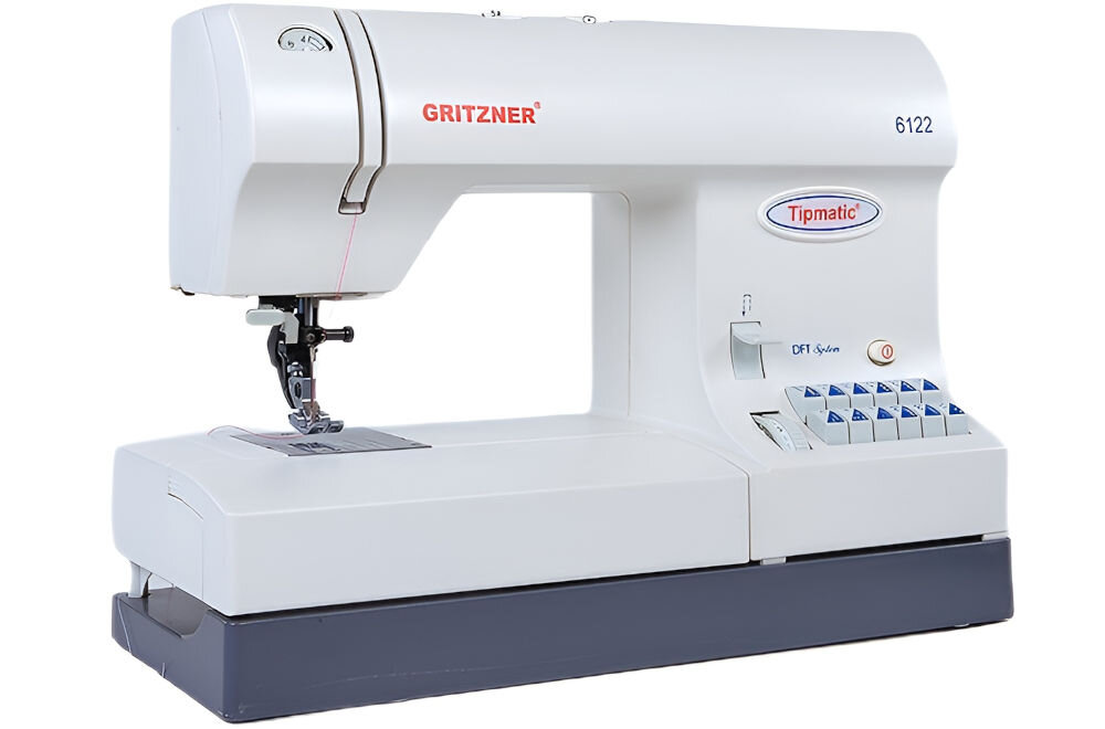 Maszyna do szycia w kolorze białym z widocznym logo \'GRITZNER\' oraz oznaczeniem modelu \'Tipmatic 6122\'. Na panelu znajdują się przyciski i pokrętła do sterowania, a także napis \'DFT System\'.