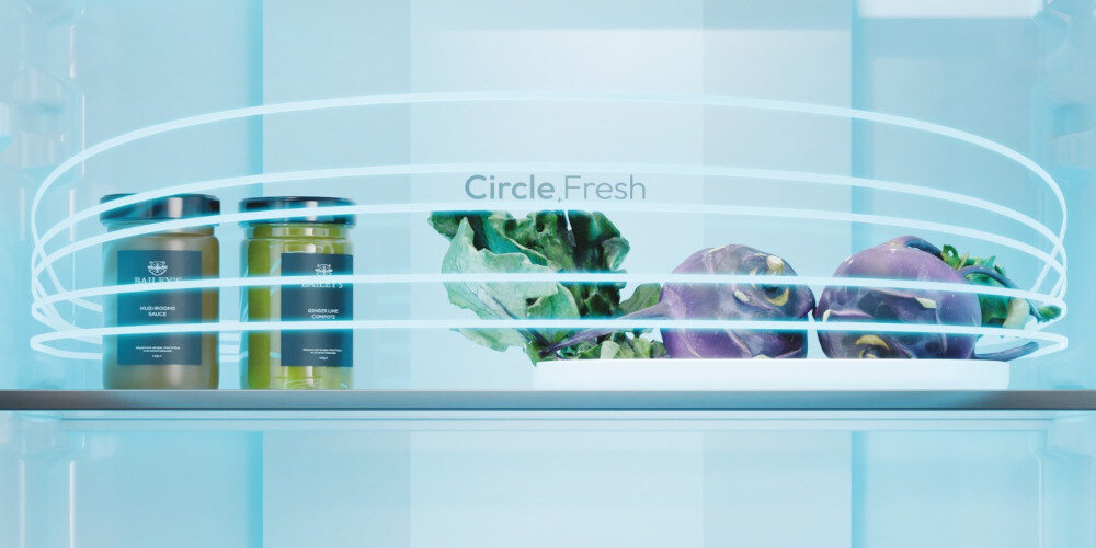 Wnętrze lodówki z napisem \'Circle Fresh\', zawierające dwa słoiki, liście sałaty i dwie fioletowe bulwy na półce.