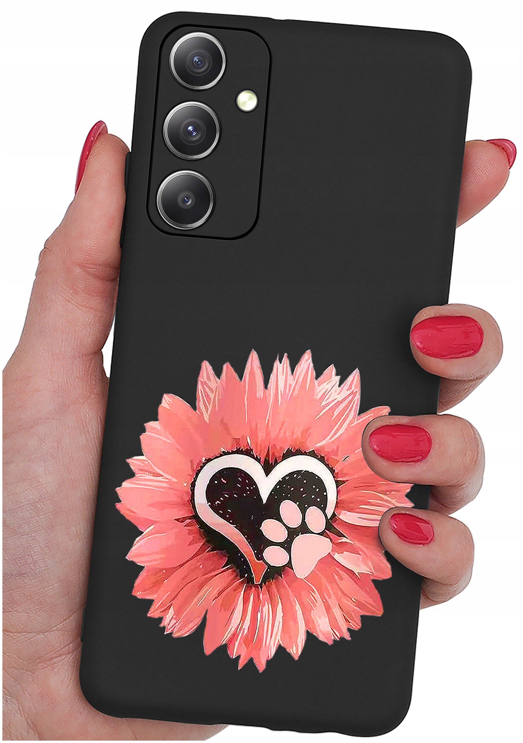 Czarne etui na telefon z trzema wycięciami na aparaty, ozdobione wzorem różowego kwiatu z sercem i łapką w środku. Etui trzymane jest w dłoni z pomalowanymi na czerwono paznokciami.