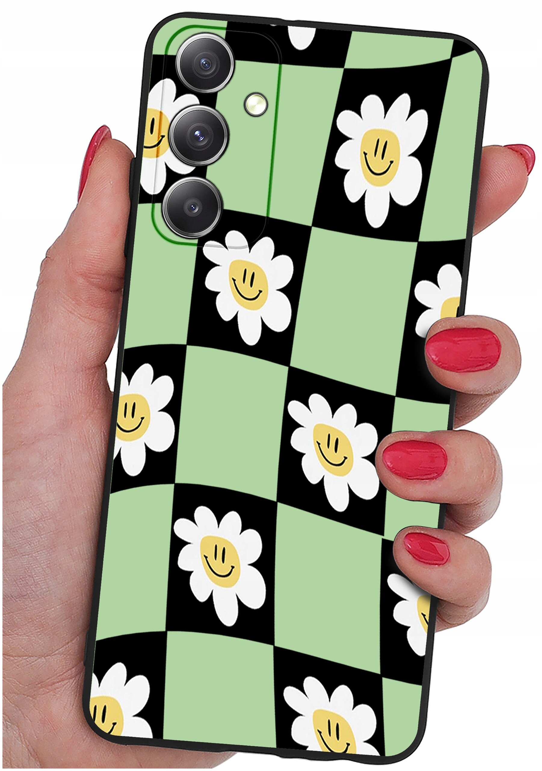 Etui na telefon z wzorem w czarno-zieloną szachownicę z białymi kwiatami o żółtych środkach. Etui trzymane jest w dłoni z pomalowanymi na czerwono paznokciami.