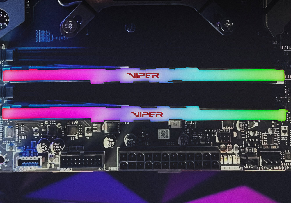 Na obrazie widoczne są dwa moduły pamięci RAM z podświetleniem RGB, zamontowane na płycie głównej. Na modułach znajduje się napis \'VIPER\'.