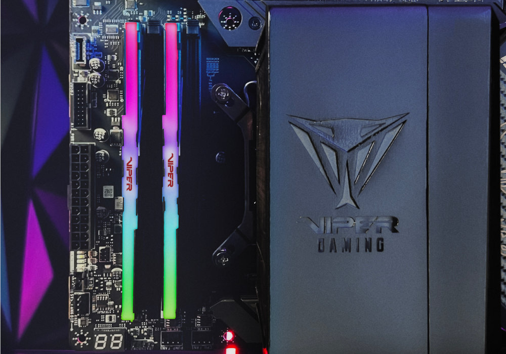Obraz przedstawia dwa moduły pamięci RAM z podświetleniem RGB zamontowane na płycie głównej. Obok widoczne jest logo \'VIPER GAMING\' na czarnym tle.