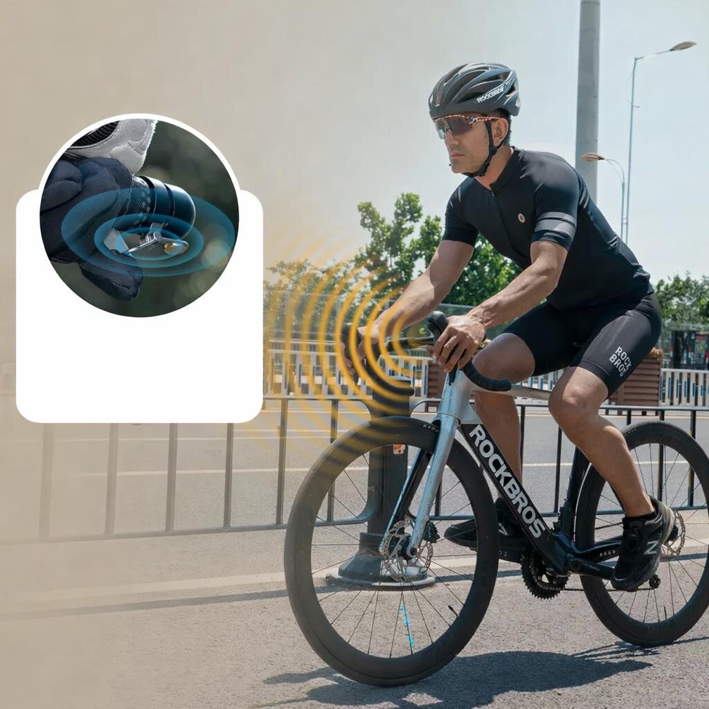 Osoba na rowerze szosowym w kasku i okularach jedzie po ulicy. Wstawka pokazuje dzwonek rowerowy zamontowany w kierownicy, z efektami dźwiękowymi w postaci fal.