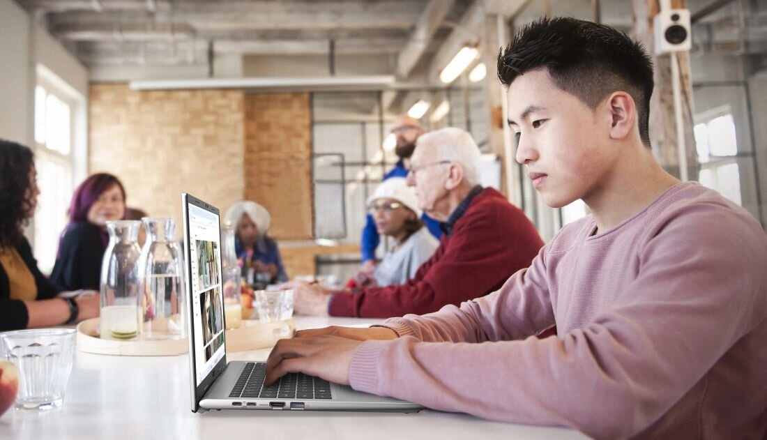 Osoba korzysta z laptopa Acer Aspire Go z portem HDMI podczas pracy w przestrzeni co-workingowej przy wspólnym stole 