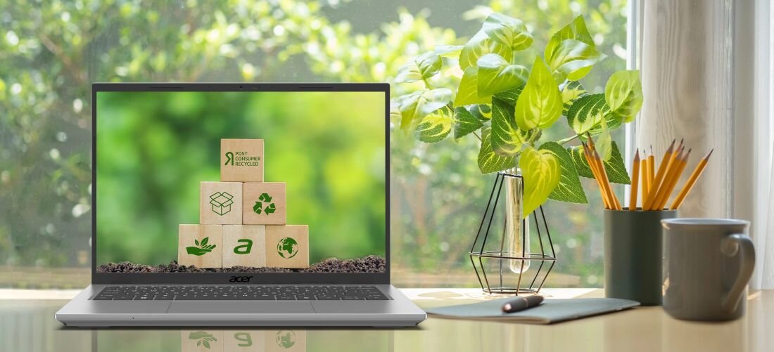 Laptop Acer Aspire Go z obudową z materiałów pochodzących z recyklingu stoi przy oknie podczas pracy biurowej 
