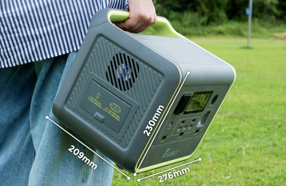 Osoba trzyma zieloną stację zasilania z uchwytem, na której widoczne są wymiary: 209mm, 230mm, 276mm. Na urządzeniu znajduje się logo i panel z przyciskami oraz wyświetlaczem.