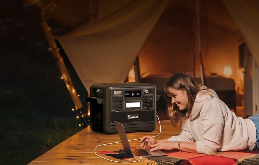 Stacja zasilania FOSSIBOT F2400 2400W Czarny, przenośna, stacja, zasilania, domowa, Kobieta pracująca na laptopie w namiocie przy stacji.