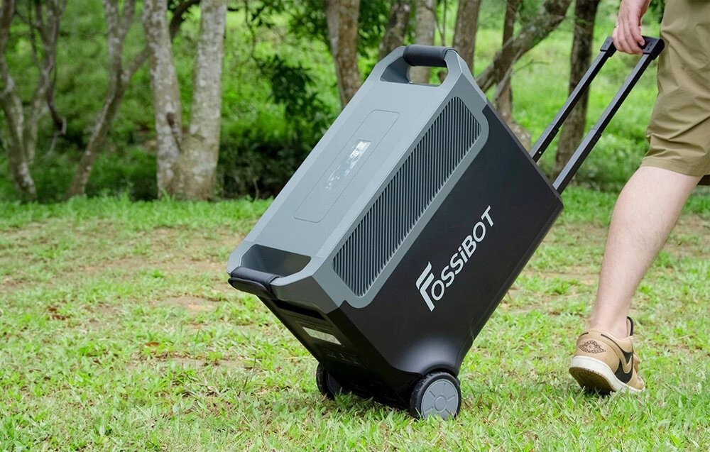 Stacja zasilania FOSSIBOT F3600 Pro 3600W Czarny trawnik osoba ciągnie stację za uchwyt idzie po trawie zakres temperatury pracy od -10 do 40°C wymiary 60,9 × 32,1 × 47,55 cm waga około 42 kg dwa kółka uchwyt funkcja stacjonarnego magazynu energii lub źródła zasilania