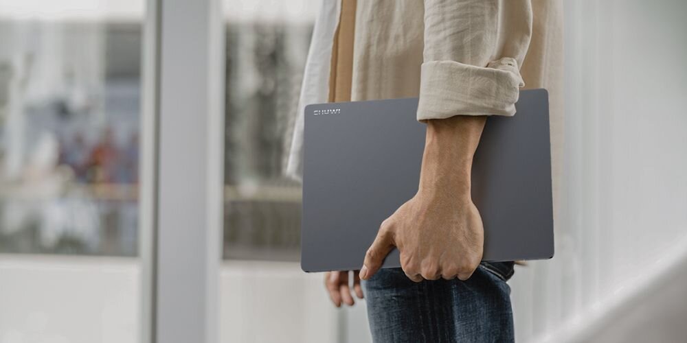 Osoba trzyma smukły srebrny laptop w dłoni pokazując lekką mobilną konstrukcję